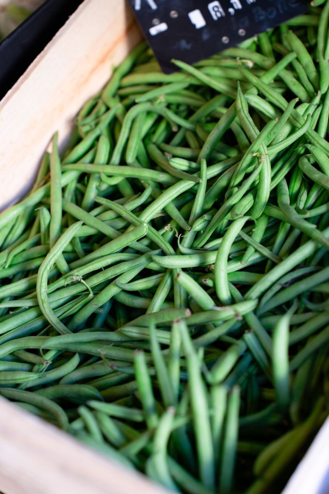 Fresh green beans in a wooden crate at a market