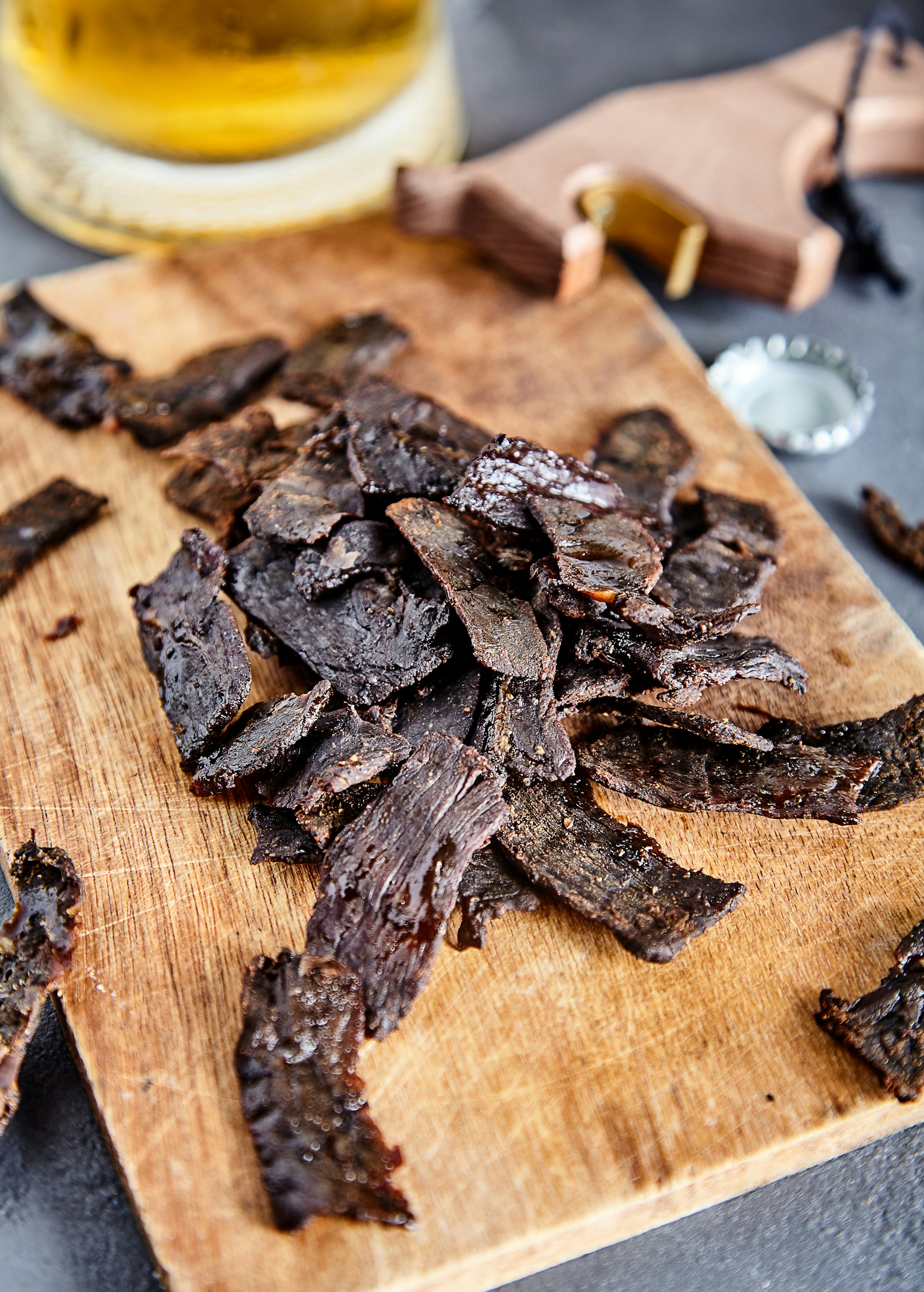Dark strips of dried, cured meat piled on a wooden board