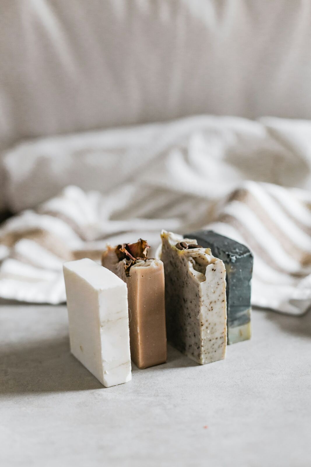 Three handmade soap bars stood on end on a white linen cloth